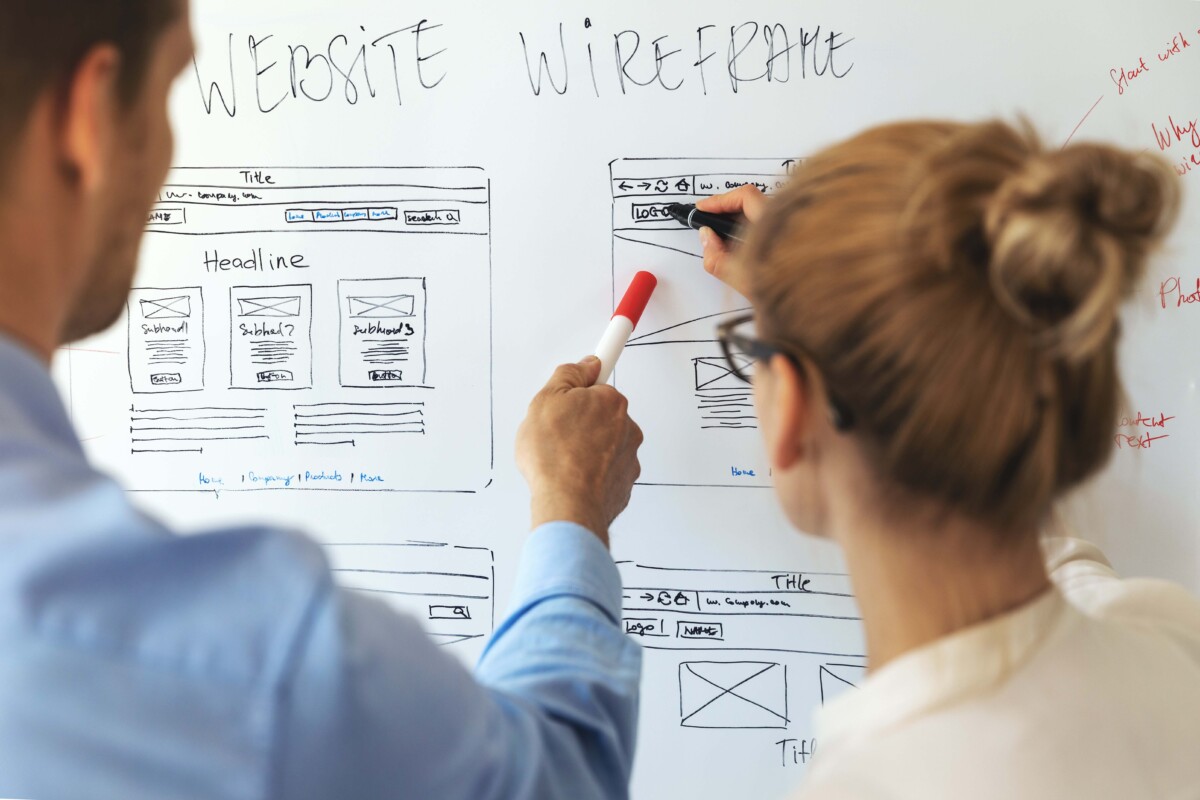Two UX designers looking at a wireframe on a whitebaord