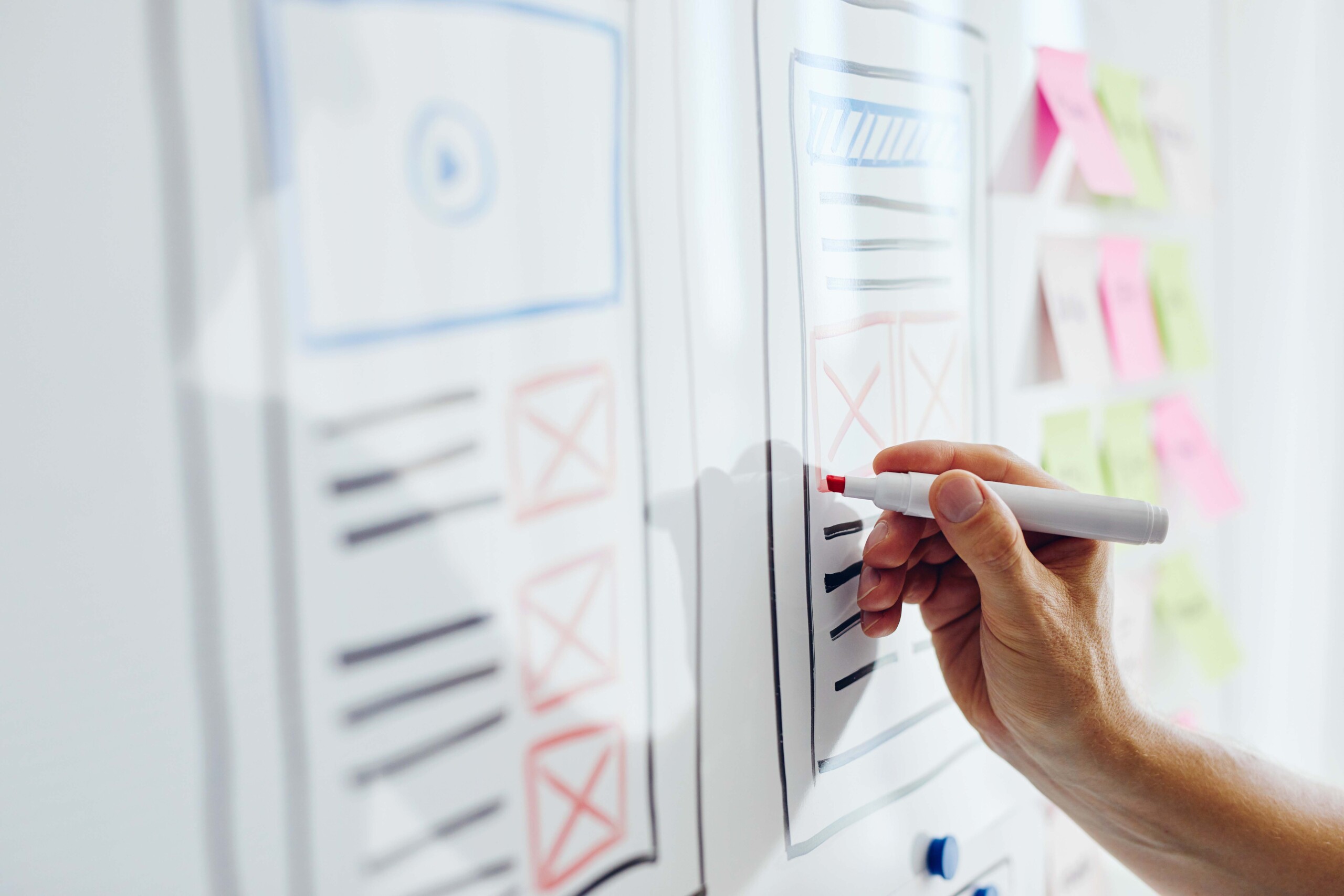 A hand creating a UX design on a whiteboard