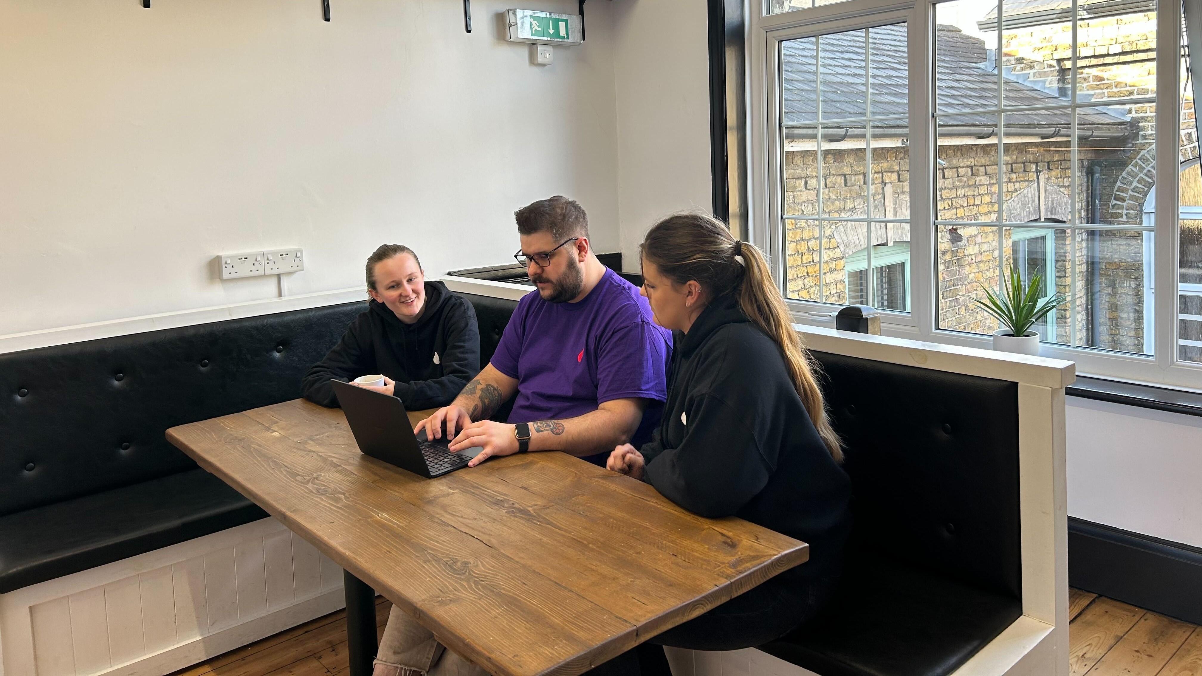 Three members of the This is Fever team working together on a laptop