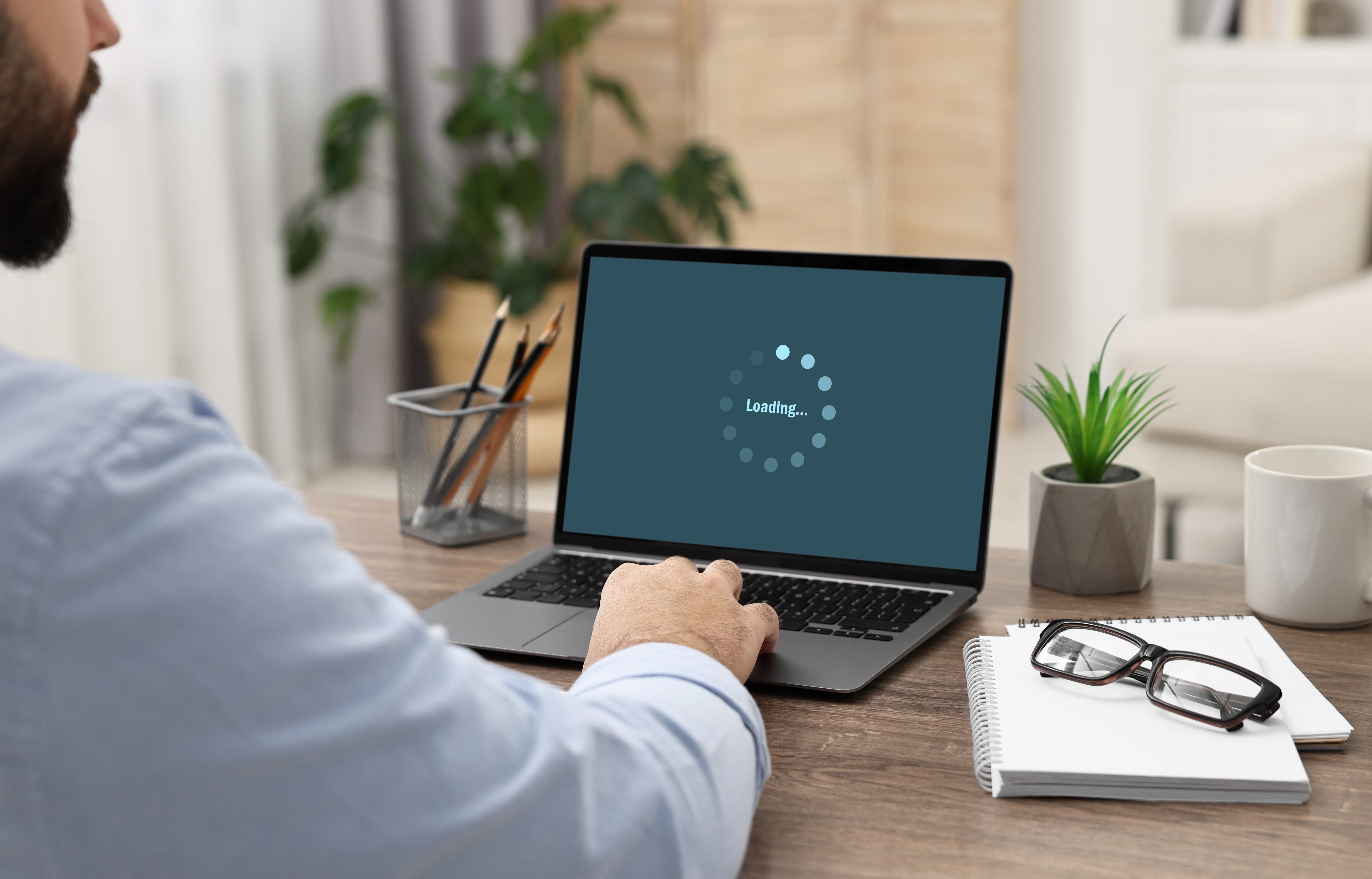 A person sitting at a computer that has a message saying that it is loading.