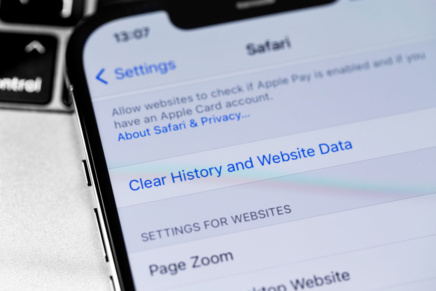 A close up of an iPhone with the Settings app open to the page displaying the option to clear history and website data for Safari