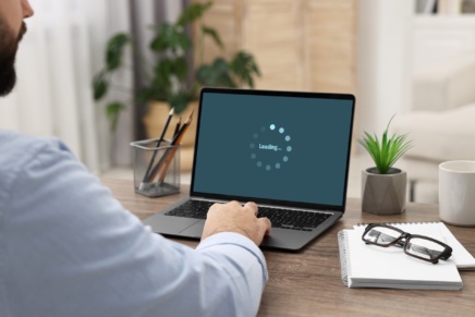 A person sitting at a computer that has a message saying that it is loading.